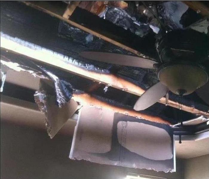 Fire damaged ceiling and ceiling fan. Charred rafters
