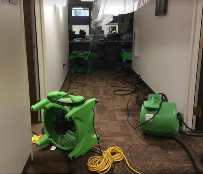 water damaged office hallway; SERVPRO restoration equipment being used to dry structure and carpet