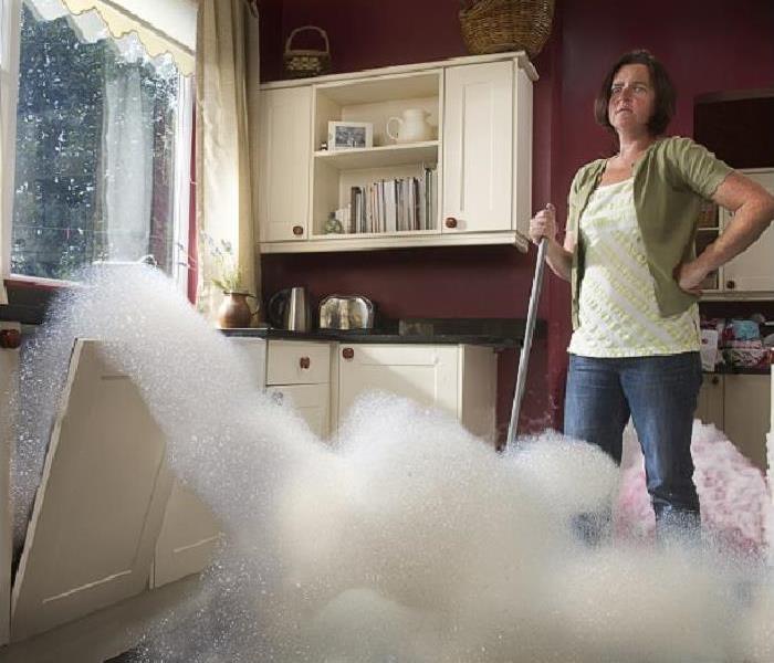 woman watching suds and water overflow from dishwasher